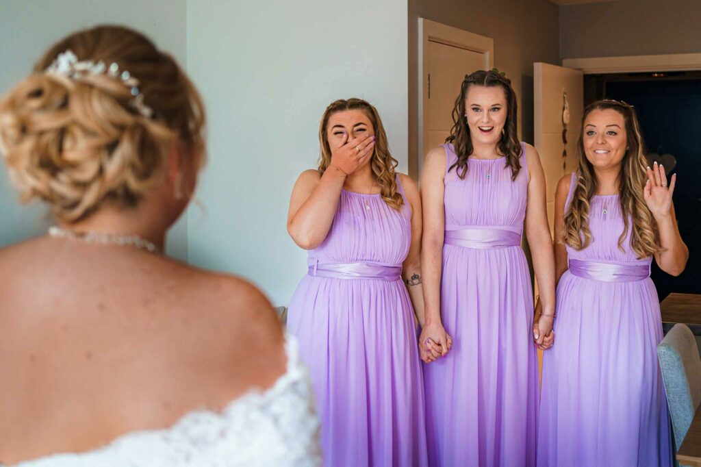 Bridesmaids happy at seeing bride for first time in dress