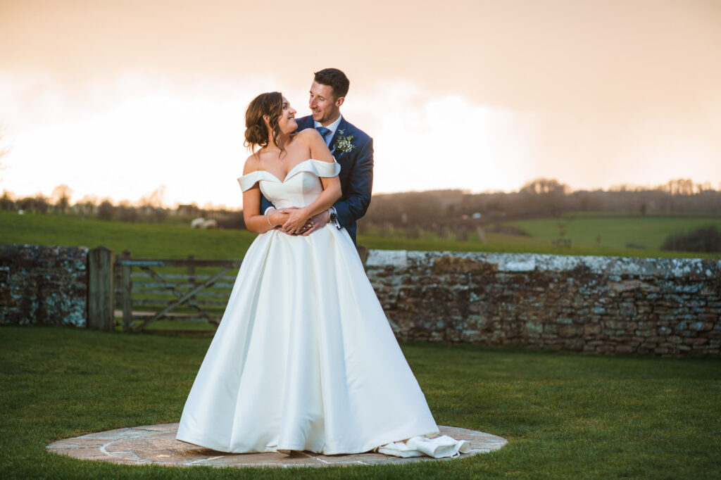 Bride and Groom cuddling at sunset on their wedding day at Dodford Manor
